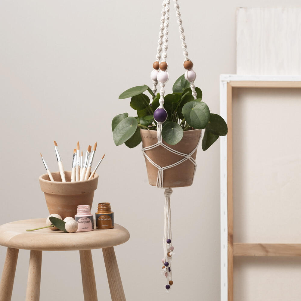 een macramé plantenhanger met zachte kleuren